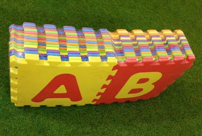 Colorful interlocking foam puzzle with letters A and B on a green grass background
