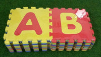 Colorful foam puzzle mat with letters A and B on a green grass background