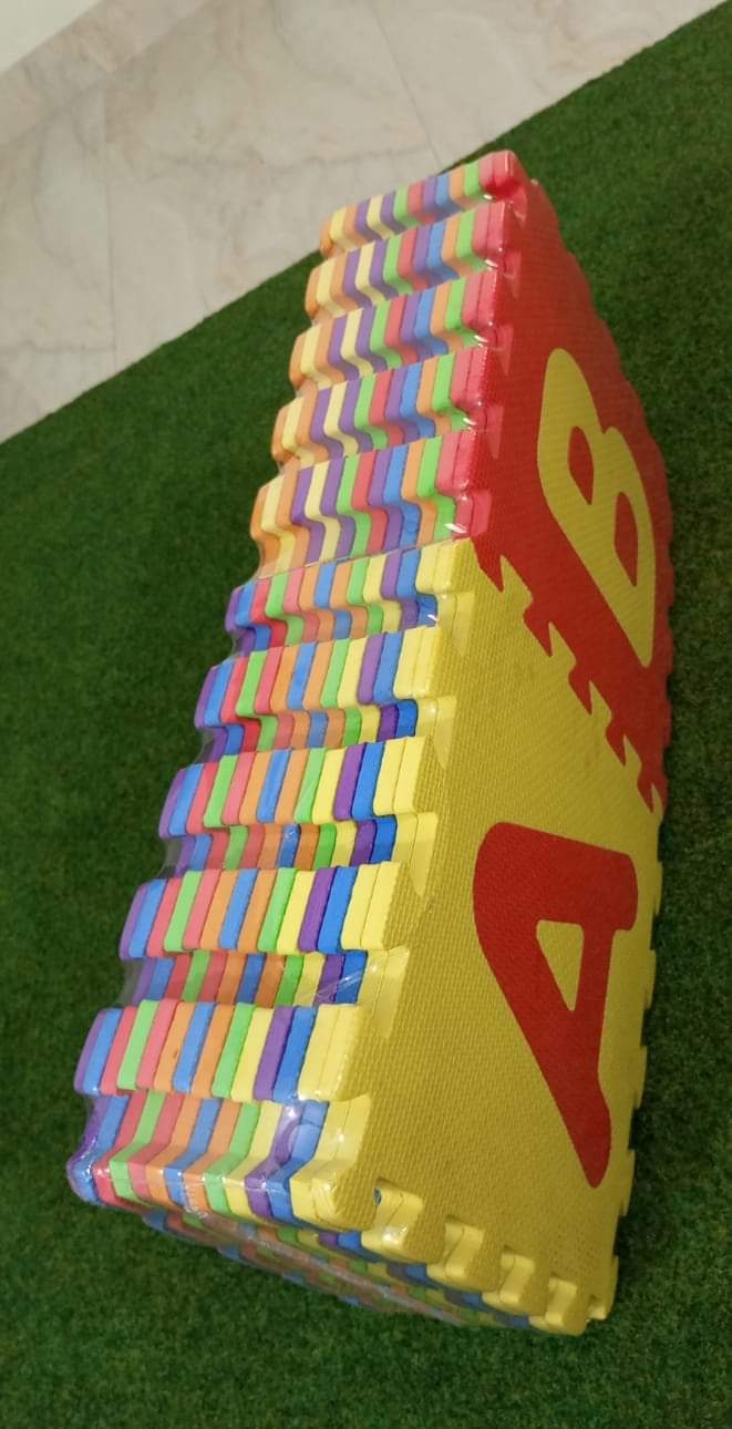 Colorful foam blocks stacked on a green surface with a red and yellow sign in the background.