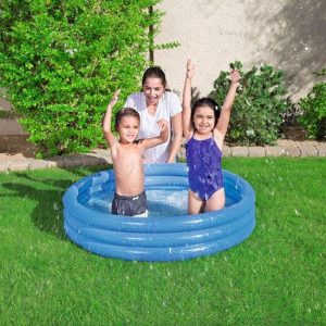 Children playing in a small inflatable pool with a woman in a backyard setting.