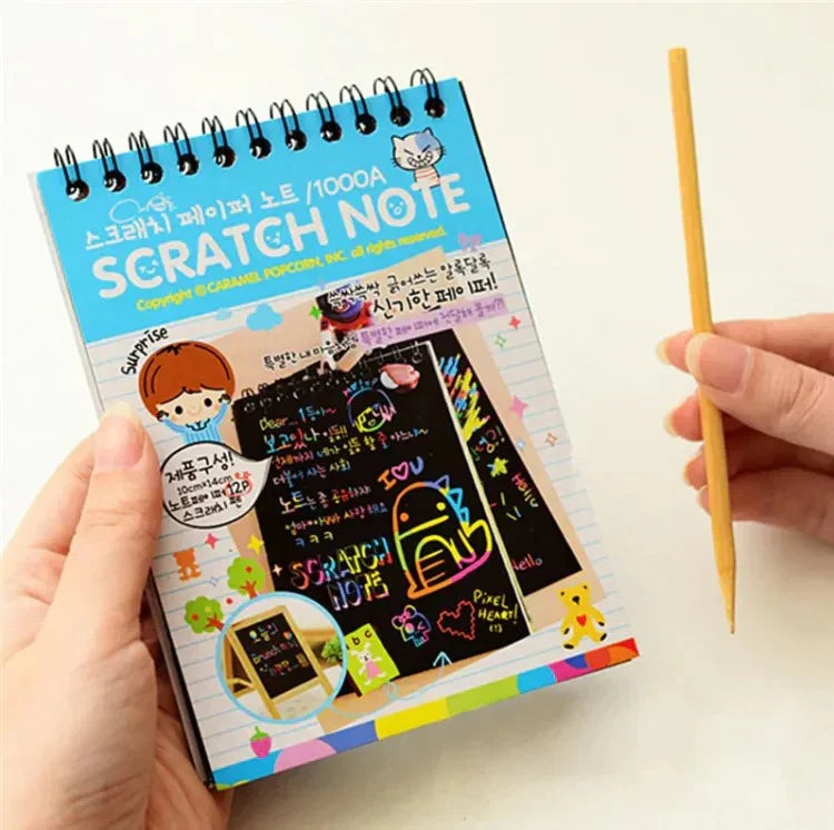 Scratch note book with colorful designs and a wooden stick on a white background