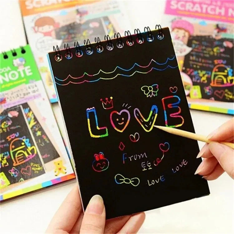 Black scratch art notebook with colorful scratch designs held by a hand, with other similar notebooks in the background.