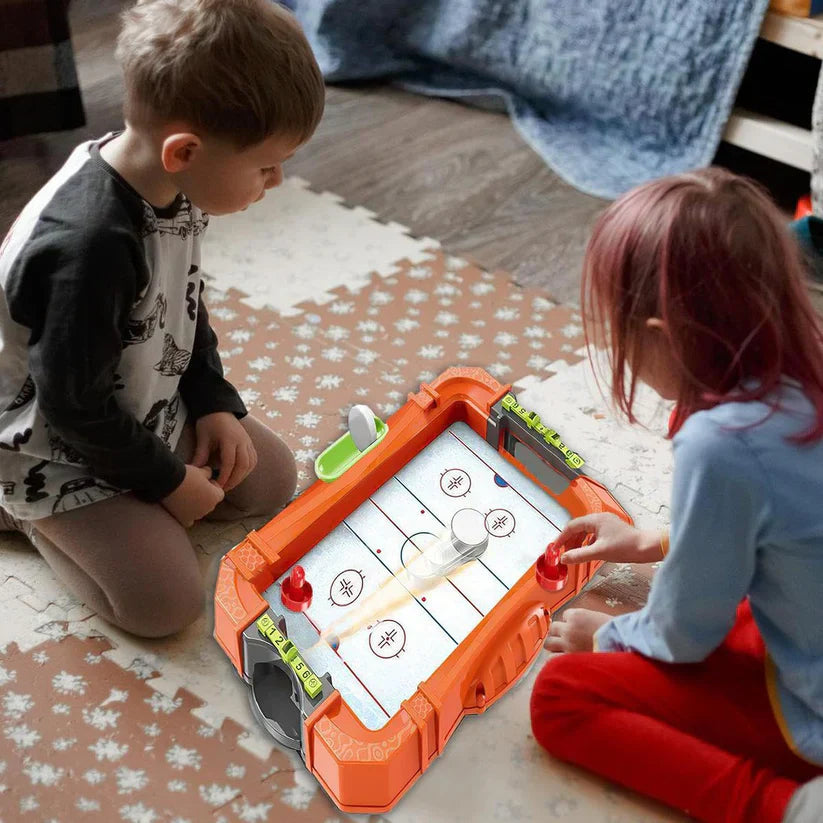 Two children playing with an air hockey table toy on a patterned rug.