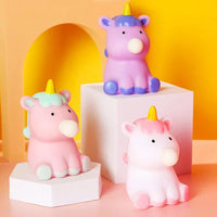 Three colorful unicorn figurines on a pink and yellow background