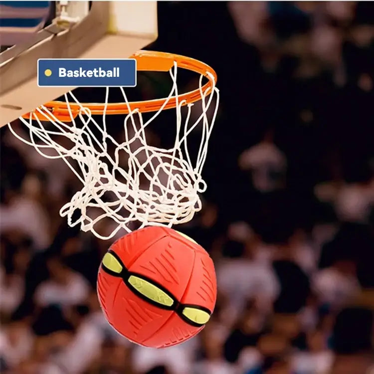 Red basketball with yellow patterns going through a basketball hoop in an indoor sports arena.