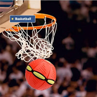 Red basketball with yellow patterns going through a basketball hoop in an indoor sports arena.