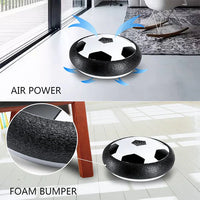 Black and white soccer ball-shaped hoverboard with air power and foam bumper features on a modern living room floor.