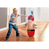 Child playing with an inflatable superhero punching bag in a room.