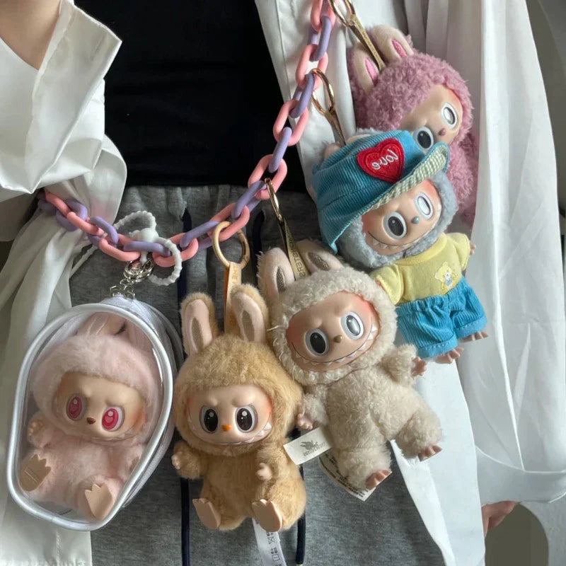 Collection of plush monkey keychains with different outfits on a chain against a neutral background.